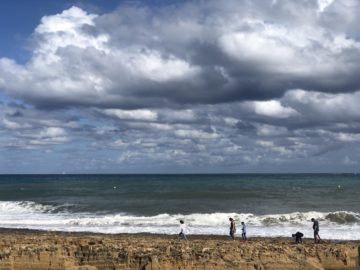 People walk with the sea behind thema
