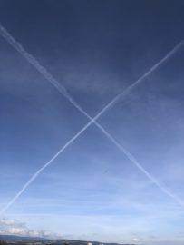 Two contrails mark an X in the sky